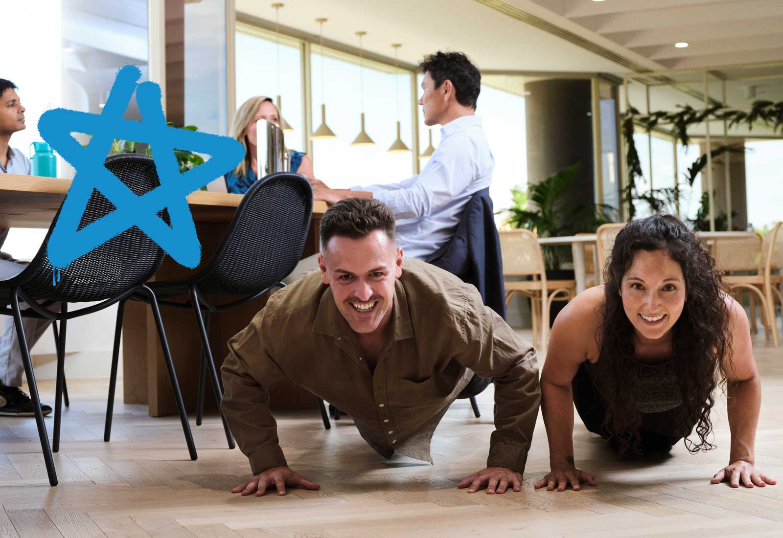 A man and a woman do Push-ups in a workplace setting, The image is overlayed with a blue graffiti star as part of the Push-Up Challenge brand campaign