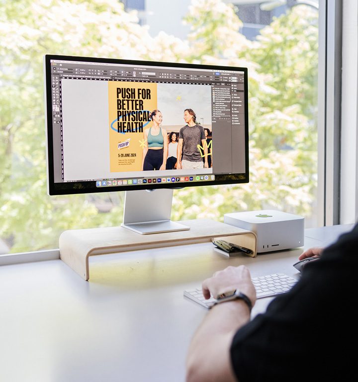 A graphic designer sits at computer in design agency and works on a not-for-profit design